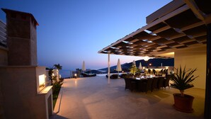 An outdoor dining area with a view of the sea, a pergola, and a potted plant. - Contemporary Villa, amazing sea views, heated infinity pool, daily maid service (Kiziltas, Kalkan)