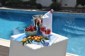A poolside setup with a wicker chair, a bowl of strawberries, a bucket of lemons, and two glasses of red drink. - 'KATIKIES 22' Luxury Detached Pissouri Beach Properties, Great Relaxing Location (Pissouri)