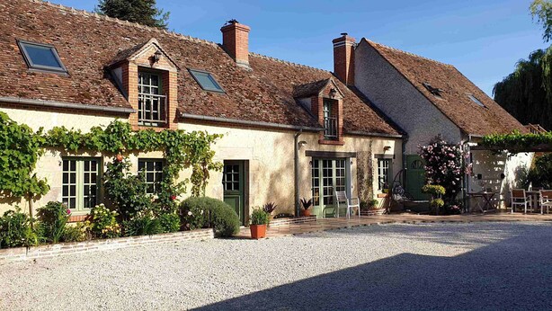 A traditional building with a gravel driveway, green shutters, and a garden area with potted plants. - Maison Cerviña (Germigny-des-Pres)