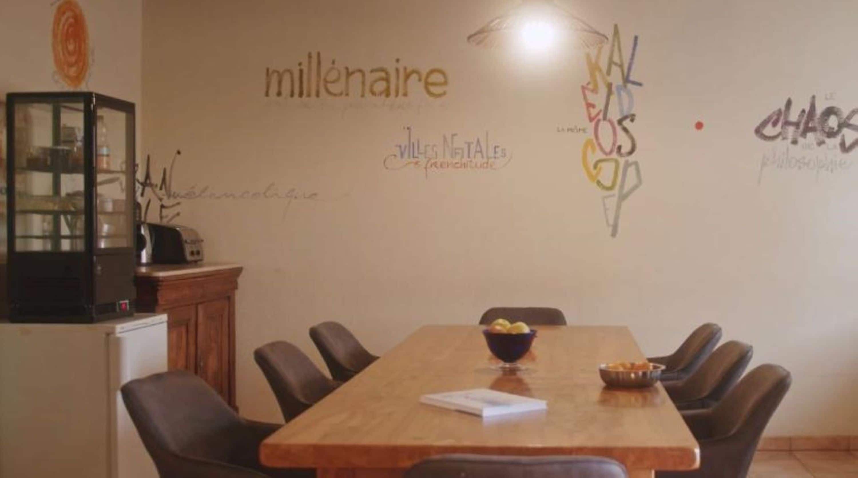 Une salle de conférence avec une longue table en bois, six chaises et un petit meuble contenant une radio.