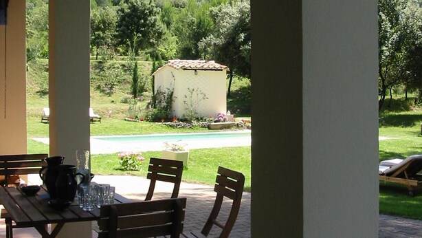 A covered patio with a table and chairs, overlooking a garden and a mountain. - Villa with Pool, Privacy and Magnificent View (Barbentane)