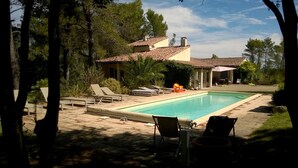 A swimming pool with lounge chairs and a hot tub, surrounded by trees and a house with a tiled roof. - Villa with Pool, Privacy and Magnificent View (Barbentane)