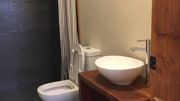 A bathroom with a white toilet, a wooden vanity with a white sink, and a shower curtain.