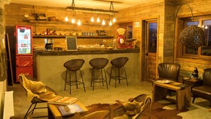 A cozy bar area with a red Coca-Cola refrigerator, wicker bar stools, and a wooden bar counter. - Hotel 381 (Panguipulli)