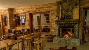 A rustic interior with wooden walls, a stone fireplace, leather furniture, and a large fur rug. - Hotel 381 (Panguipulli)