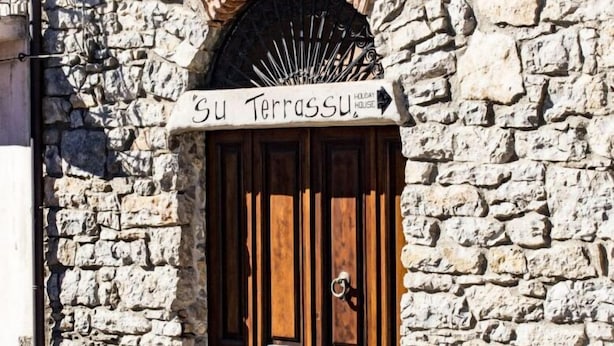 A stone building with a wooden double door and a sign above it that reads "Su Terrassu". - Su Terrassu by All4sardinia  (Ulassai)