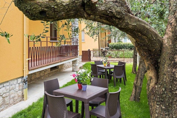 An outdoor patio with wicker furniture and a table with a flower centerpiece.