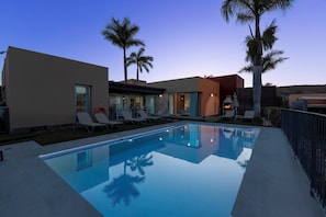A modern pool area with clear blue water, lounge chairs, and palm trees. - Par 4 Home 7 Salobre by VillaGranCanaria (San Bartolomé de Tirajana)