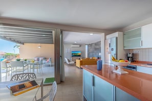 A modern kitchen with a central island, a dining area with a table and chairs, and a living room with a sofa and TV. - Par 4 Home 7 Salobre by VillaGranCanaria (San Bartolomé de Tirajana)