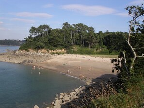 A beach with clear water, rocky shoreline, and dense trees in the background. - Seaside gîte for 4 people (Trédrez-Locquémeau)