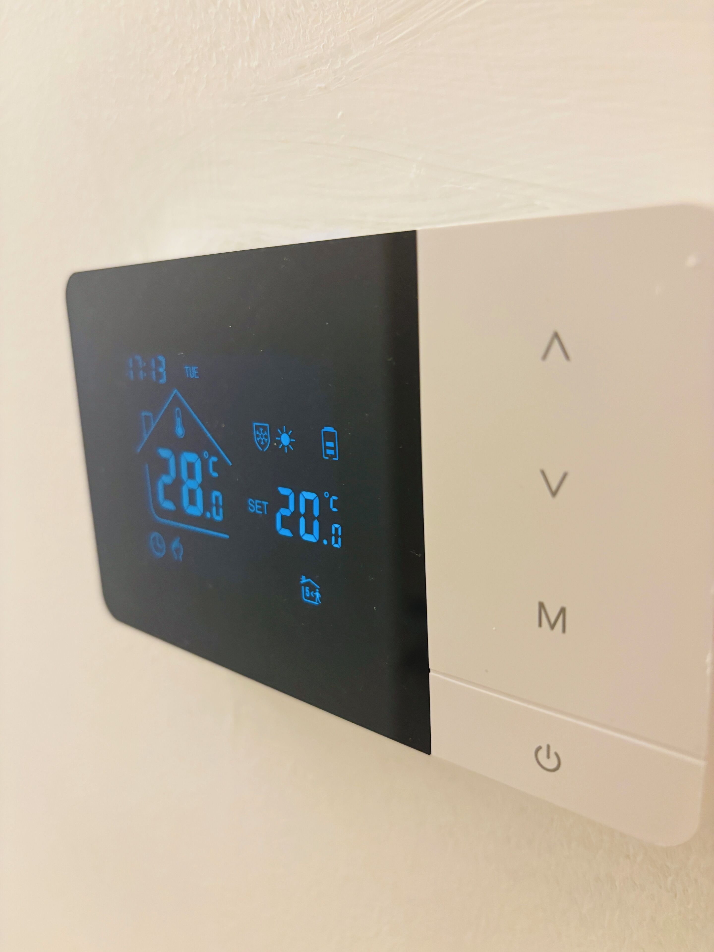 A thermostat with a digital display showing 28°C and a set temperature of 20°C.