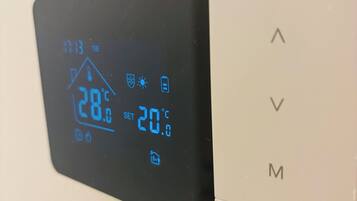 A thermostat with a digital display showing 28°C and a set temperature of 20°C.