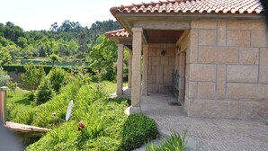 A stone building with a tiled roof, surrounded by lush greenery and a stone pathway. - Refuge with swimming pool, playground and incredible views - Pure Tranquillity (celorico de basto)