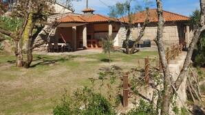 A stone building with a tiled roof, a covered patio, and a grassy yard. - Refuge with swimming pool, playground and incredible views - Pure Tranquillity (celorico de basto)