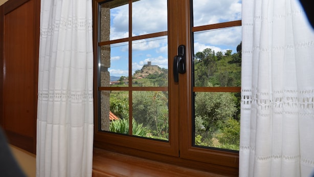 A room with a large window offering a view of a hill with a castle-like structure. - Refuge with swimming pool, playground and incredible views - Pure Tranquillity (celorico de basto)