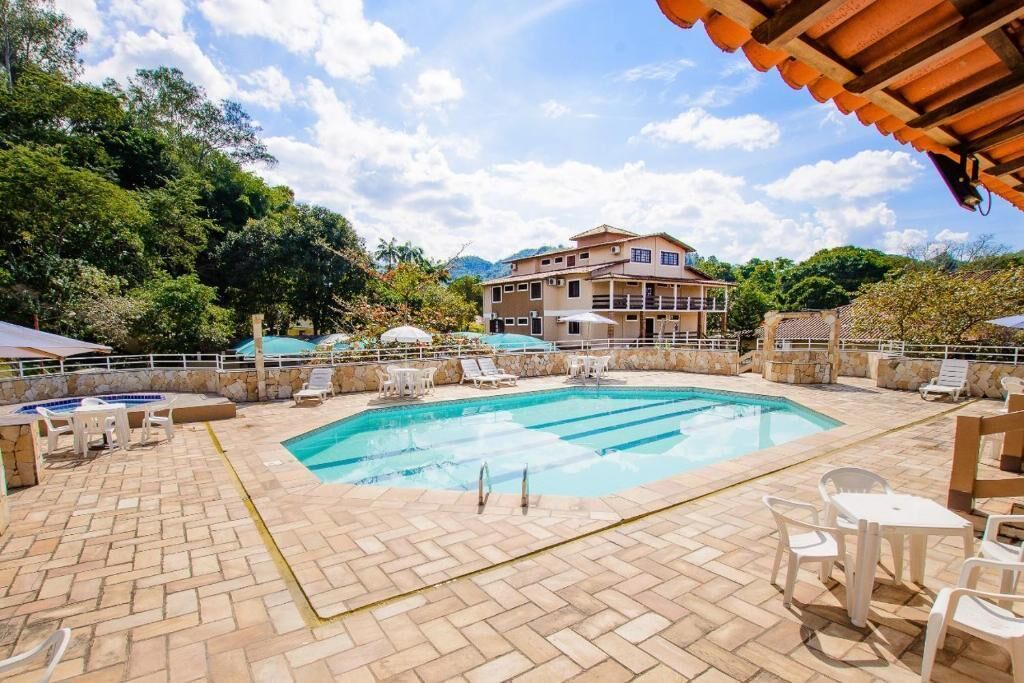 Una piscina con sillas de descanso y sombrillas, rodeada por un patio de piedra.