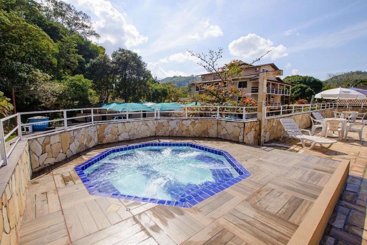 A hot tub surrounded by stone walls, with a wooden deck and lounge chairs.