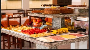Un bufé con diversas opciones de comida, incluyendo frutas, carnes y pasteles.