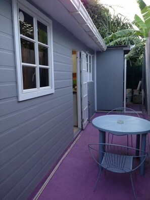 Un patio con una mesa redonda y sillas, una ventana y una puerta que da a un espacio interior.