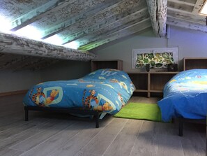 A small attic bedroom with two beds, a green rug, and a shelf with a plant and a speaker. - In the heart of beautiful Tuscany, Spa, Culture and Good Food (Monsummano Terme)