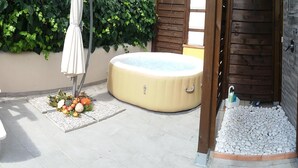 Eine Terrasse mit weißen Stühlen, einem Whirlpool und einer dekorativen Anordnung aus Obst und Gemüse.