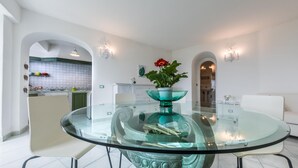 Un comedor moderno con una mesa de vidrio, sillas blancas y un cuenco decorativo como centro de mesa.