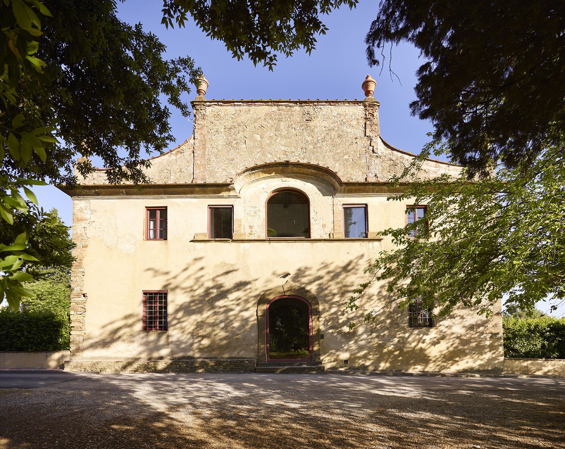 Um edifício histórico com uma entrada central em arco, várias janelas e um pináculo decorativo no telhado.