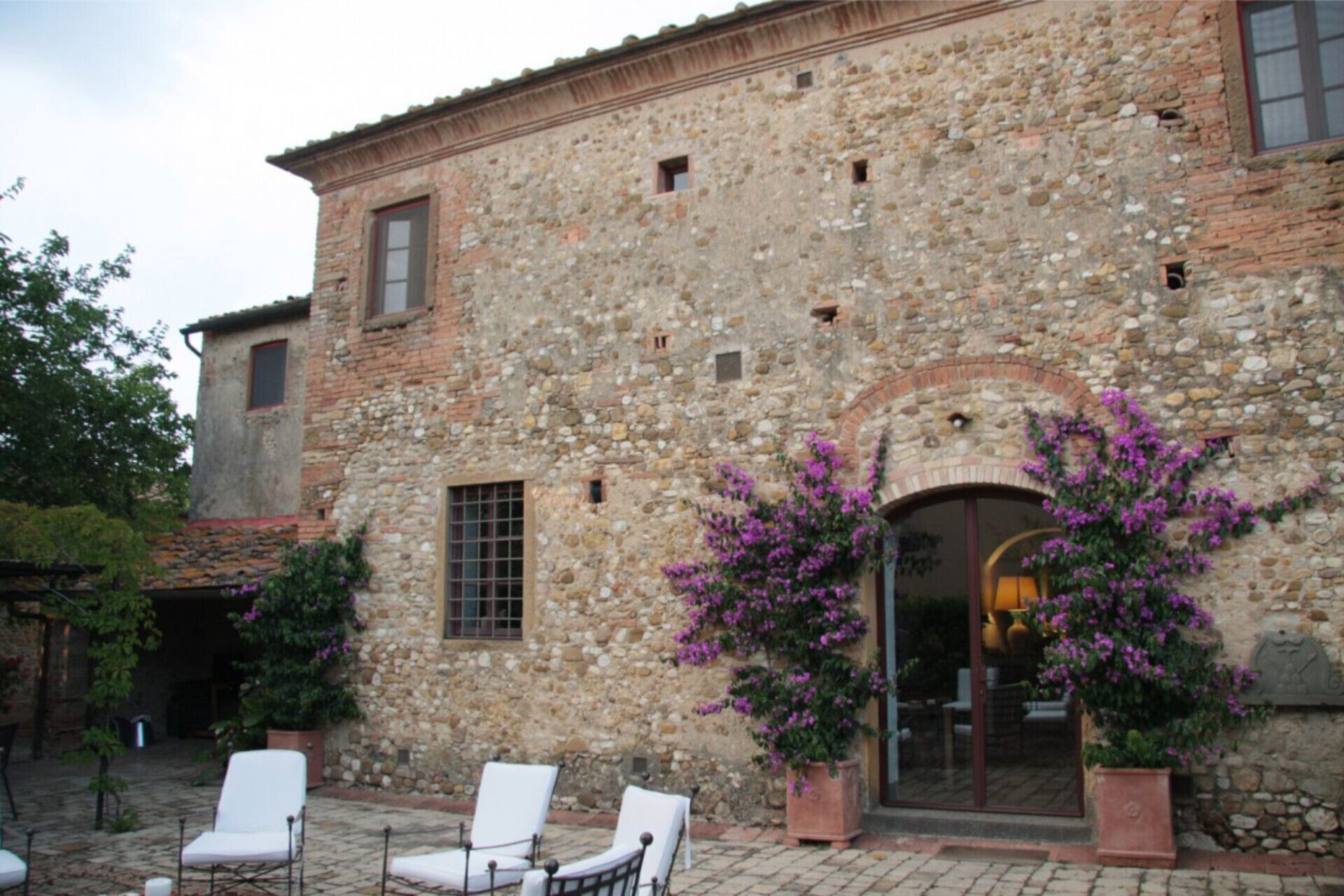 A stone building with a courtyard, featuring a central archway and potted plants.