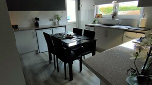 Ett modernt kök med matplats, inrett i svart och vitt, med ett fönster som vetter mot en fin utsikt och en diskho.