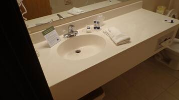 Ett hotellbadrum med handfat, spegel och hygienartiklar.