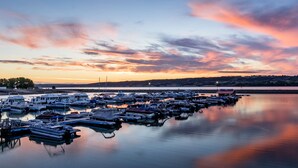 A marina with various boats docked at calm waters during sunset.