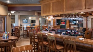 A bar area with wooden furniture, a bar counter, and hanging wine glasses.