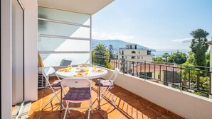 Un balcon avec une table dressée pour le petit-déjeuner, offrant une vue panoramique sur les bâtiments et les montagnes.