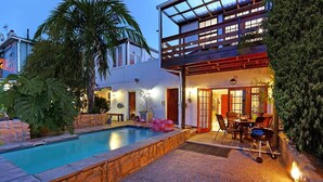 A modern house with a swimming pool, outdoor seating, and a covered patio area. - Angel Cottage (Cape Town)