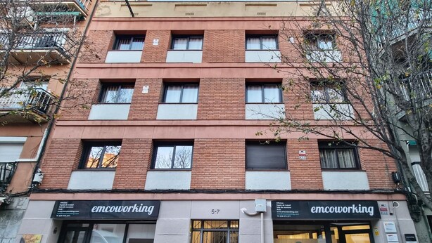 A multi-story building with 'emcoworking' signage on the ground floor.