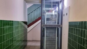 A staircase with green tiled walls, a metal railing, and a sign for 'europa firä apartments'.