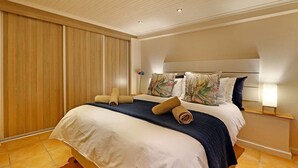 Hotellihuone, jossa on suuri sänky, toisessa seinässä puupanelointi ja yöpöydällä lamppu.