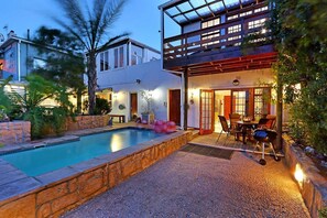 A modern house with a swimming pool, outdoor seating, and a covered patio. - Skye Cottage (Cape Town)