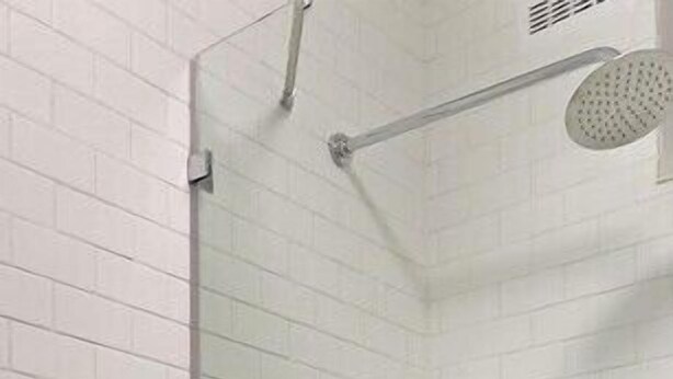 Un baño moderno con azulejos blancos tipo metro, cabina de ducha de vidrio, inodoro y lavamanos.