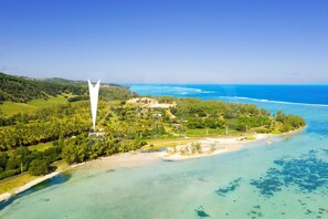 An aerial view of a coastal area with a prominent white tower, lush greenery, and clear blue waters. - Villa La Cocoteraie, 400 sqm, close to the beach, in a beautiful garden (Baie du Cap)
