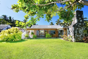 A house with a stone chimney, a covered patio, and a well-maintained lawn.