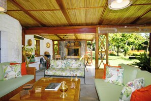 A cozy outdoor seating area with a stone wall, wooden furniture, and a view of the garden.