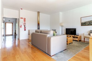 A modern living room with a sofa, a TV, and a fireplace. - A Retreat with a Natural Pool Bathed by the Douro River (Gondomar)