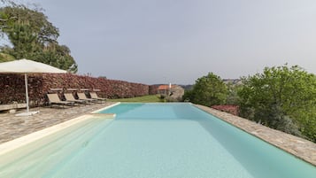 Piscina com espreguiçadeiras e pérgola.