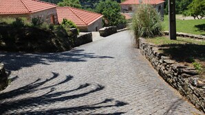 A cobblestone path leading to traditional stone buildings with red-tiled roofs.