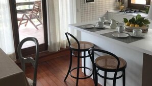 Una cocina moderna con un salpicadero de azulejos blancos, una isla central con taburetes y un comedor con mesa y sillas.