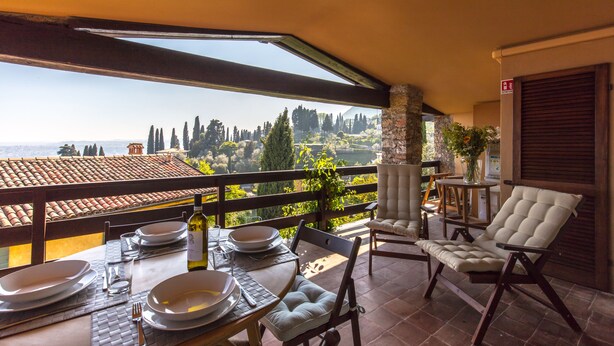 Una terraza con mesa lista para comer, una silla con cojín y vistas al campo.