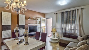 A modern living room with a dining area, a sofa set, a TV, and decorative items. - Luxury apartment in Puerto Rico (Mogán) (Mogán)