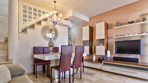 A modern living room with a dining area, a staircase, and a TV mounted on the wall. - Luxury apartment in Puerto Rico (Mogán) (Mogán)