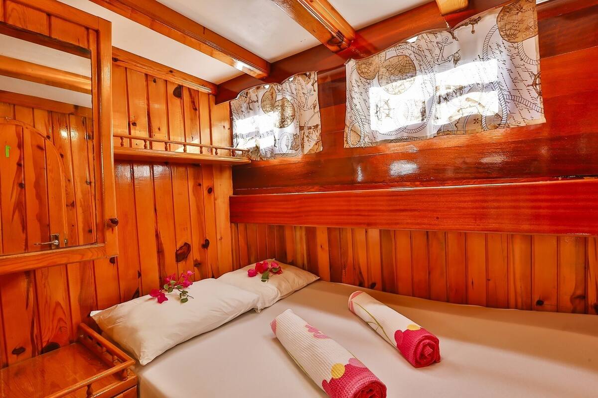 Una habitación de cabaña de madera con una cama, un armario de madera y una ventana con diseño de mapa.